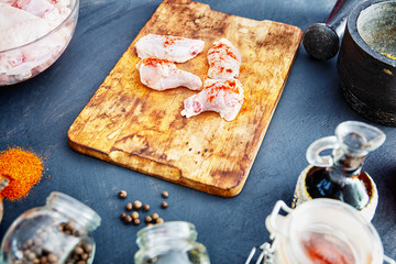 Raw chicken wings with spices on a wooden cutting board