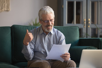 Happy old grandfather reading postal mail letter showing thumbs up