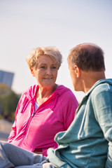 Naklejka premium Active senior couple talking while resting on bench at park