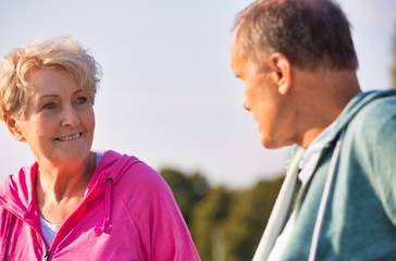 Obraz premium Active senior couple talking while resting on bench at park