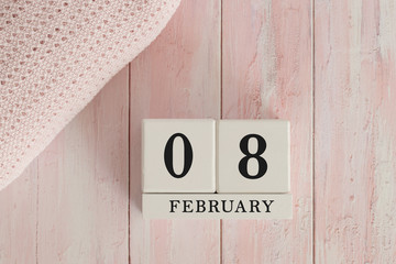 8 February Date on Cubes. Date on painted pink wood, next to baby blanket. Theme of baby due dates and birth dates.