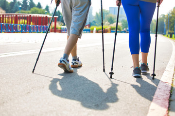 Senior couple with hiking poles walking on footpath at park