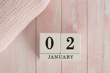 2 January Date on Cubes. Date on painted pink wood, next to baby blanket. Theme of baby due dates and birth dates.