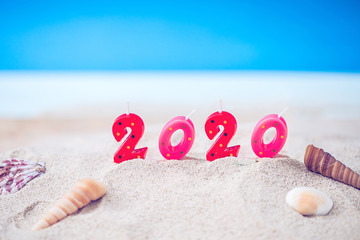 Colorful Candle Number 2 0 2 0 Over Blurred Blue Sea and Sand Beach with Clear Blue Sky ,Image for New Year 20 20 Celebration Decorative Concept.