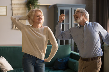 Naklejka premium Happy active retired elder couple dancing together in living room