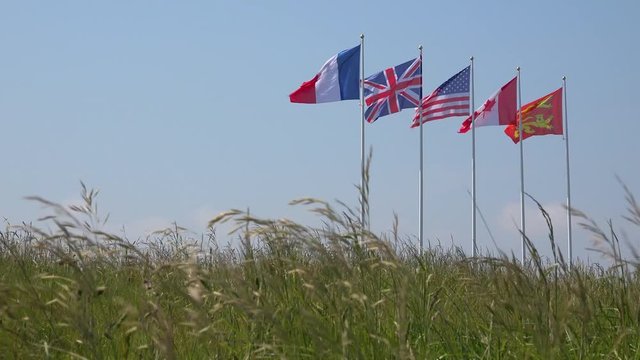 The flags of France, Great Britain, The US, Canada and Normandy fly over the World War Two site of the D-Day landings.