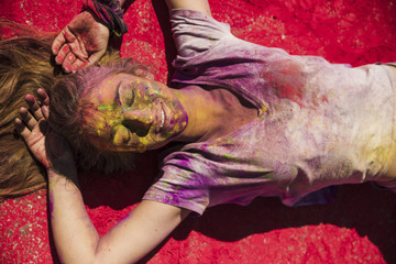 An overhead view of young women lying on red holi powder