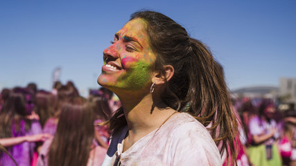 Obraz premium Smiling young woman's face painted with holi color