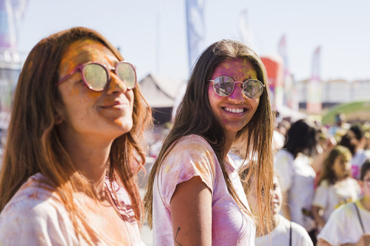 Two young women wearing sunglasses with holi powder on face