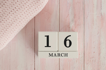 16 March Date on Cubes. Date on painted pink wood, next to baby blanket. Theme of baby due dates and birth dates.