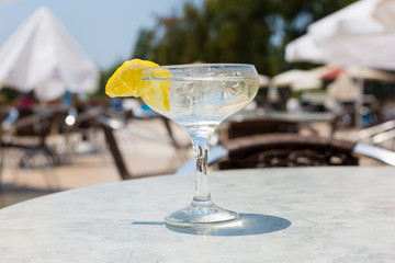 Wine glass with an alcoholic cocktail and lemon. Glass cup with alcohol and a slice of lemon ice.