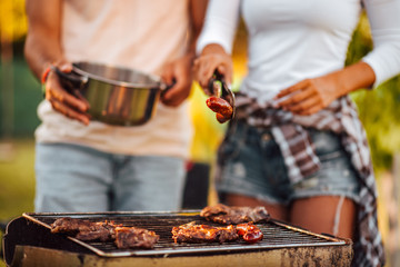 Close-up image of friends making barbecue outdoors, close-up.