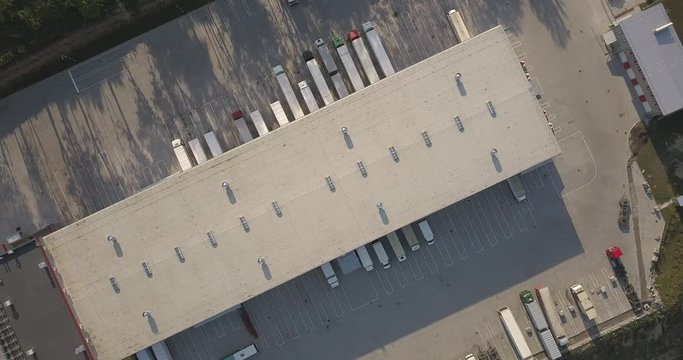 Aerial view of goods warehouse. Logistics center in industrial city zone from above. Aerial view of trucks loading at logistic center. View from drone