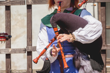 Woman in medieval clothes playing on a bagpipe_