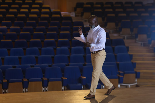 Businessman with holding script walking in a auditorium 