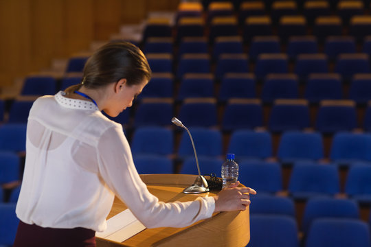Businesswoman looking in script  and trying to speak in the empty auditorium 