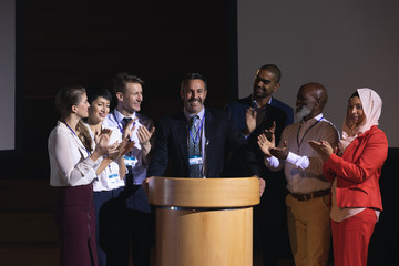 Business colleagues clapping hand for there colleague  for the success in the auditorium stage