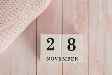28 November Date on Cubes. Date on painted pink wood, next to baby blanket. Theme of baby due dates and birth dates.