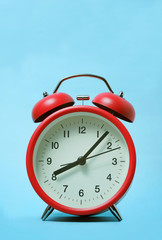 Red alarm clock on light blue color background