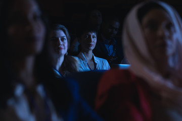 Businesswoman holding laptop and listening to the presentation in auditorium