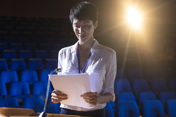 Businesswoman standing at podium on stage in auditorium