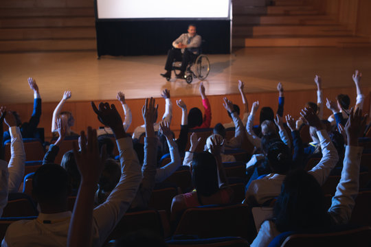 Businessman sitting on a wheelchair and giving presentation to the audience - Powered by Adobe