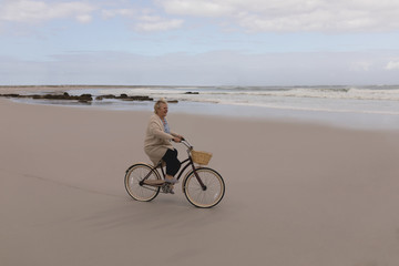 Fototapeta premium Happy senior woman riding bicycle at the beach 