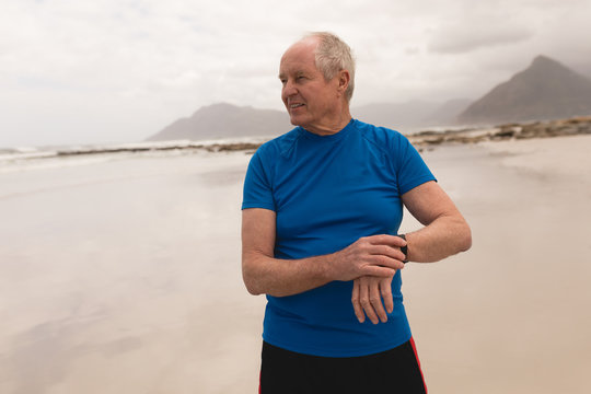 Happy senior man using smartwatch at the beach - Powered by Adobe