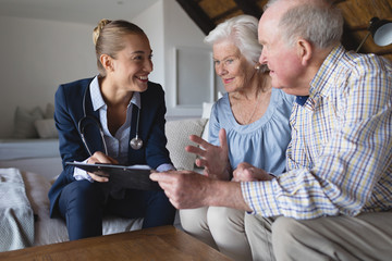 Female doctor and senior couple discussing over clipboard