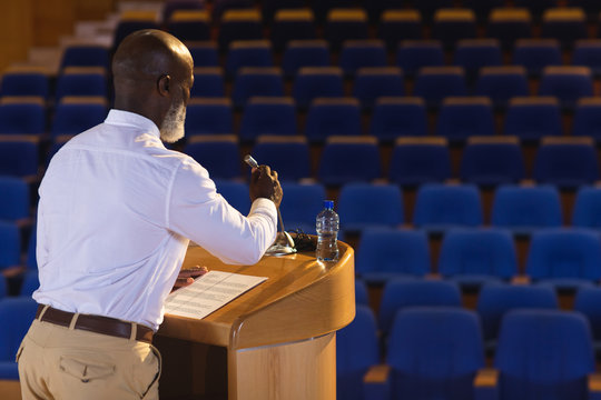 Matured businessman practicing for speech in the empty auditorium