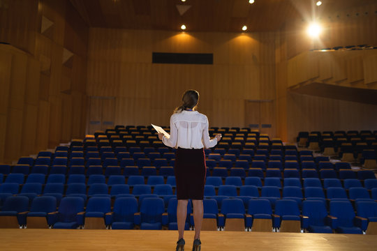 Businesswoman practicing and learning script while standing in the auditorium
