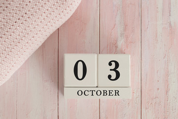 3 October Date on Cubes. Date on painted pink wood, next to baby blanket. Theme of baby due dates and birth dates.