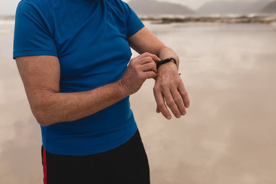 Senior man using smartwatch at the beach