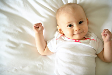 Cute happy baby girl in diaper on bed