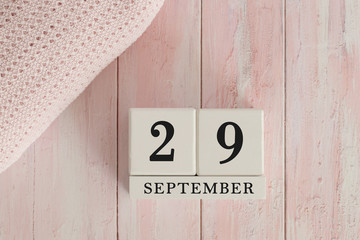 29 September Date on Cubes. Date on painted pink wood, next to baby blanket. Theme of baby due dates and birth dates.