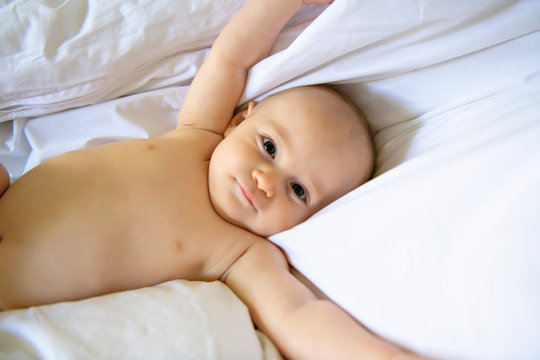 Cute baby girl in diaper on bed