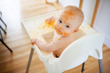 A Little baby eating her dinner and making a mess