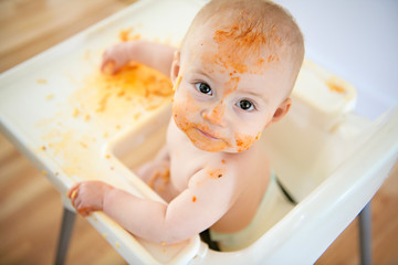 A Little baby eating her dinner and making a mess