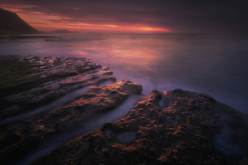dark seascape in the coast with rocks at dusk