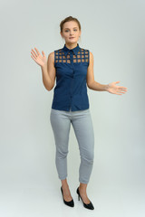 Full length studio portrait of a pretty young woman girl in a business suit on a white background. He stands right in front of the camera, explains, shows his hands with emotions.