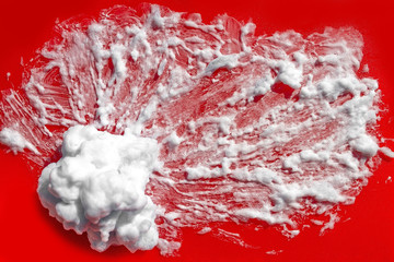  Piled shaving foam. On a red background. Macro. View from above.