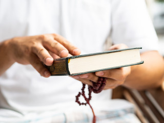 Young man holds closed Quran book. Islamic concept