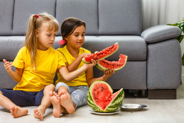 Child eating watermelon, two little girls eat watermelon at home