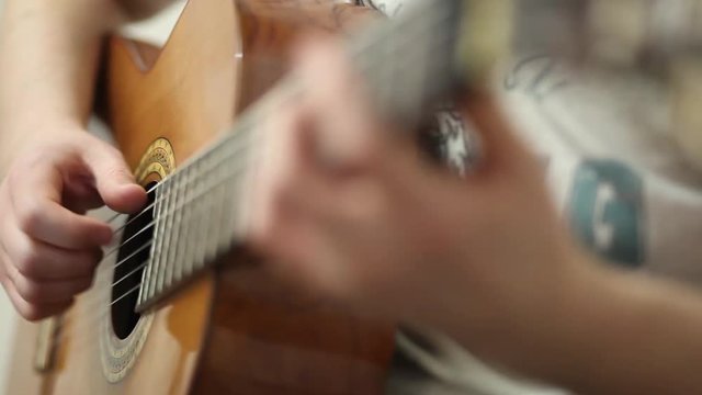 The guitarist plays an acoustic guitar. Guitarist hand and fretboard closeup