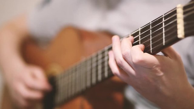 The guitarist plays an acoustic guitar. Guitarist hand and fretboard closeup