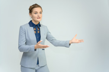 Studio photo a waist-high portrait of a pretty young woman girl in a business suit on a white background. He stands right in front of the camera, explains, with emotion.