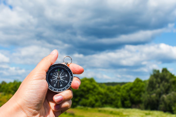 compass in hand close-up on the background of the summer landscape