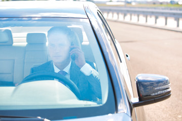 Mature businessman talking on mobile phone while driving car