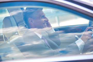 Mature businessman talking on mobile phone while driving car