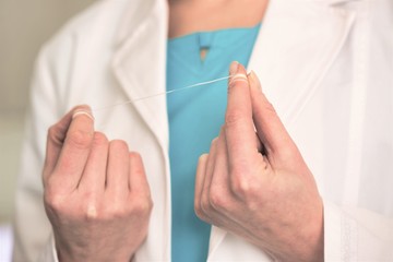 Midsection of dentist holding dental floss at clinic